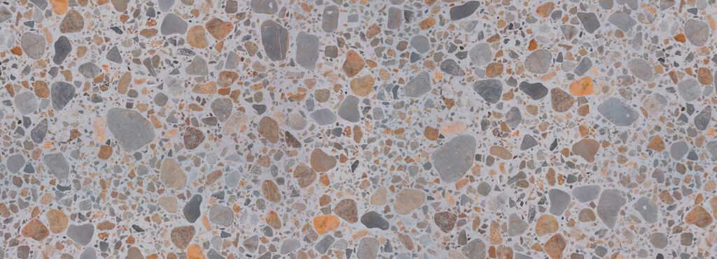 Terrazzo floor with multicolored pebbles in gray, beige, and orange embedded in light gray concrete.