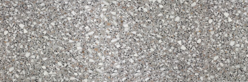 Close-up of terrazzo surface with white, gray, and black aggregate chips embedded in cement.