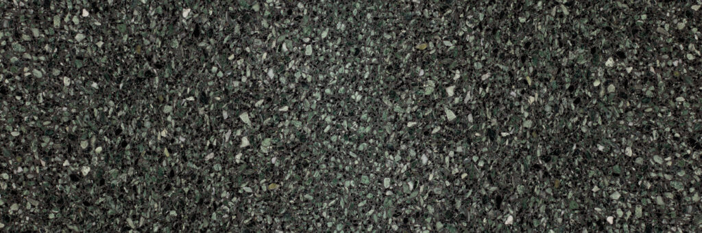 Close-up of a dark green terrazzo flooring with small irregular light-colored stones scattered throughout.