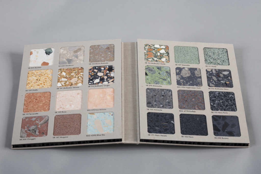 Open color swatch book showing terrazzo tile samples with labeled names on each square panel across two pages.