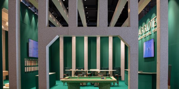 Exhibition booth with speckled stone columns forming arches around a pool table on a green floor and walls.