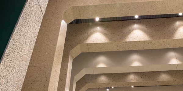 Interior architectural space featuring a terrazzo-clad stairwell with angled walls and embedded ceiling lights.